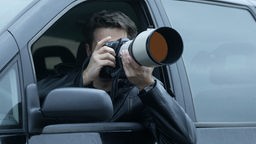 Mann fotografiert aus einem Auto-Fenster mit einem Teleobjektiv