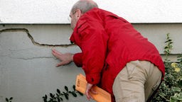 Ein Mitarbeiter des Bergamtes untersucht eine Hauswand