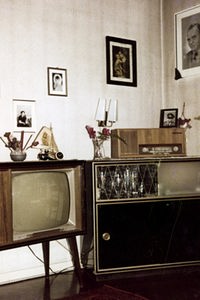 Wohnzimmer mit Fernseher, Musiktruhe und Familienfotos an den Wänden