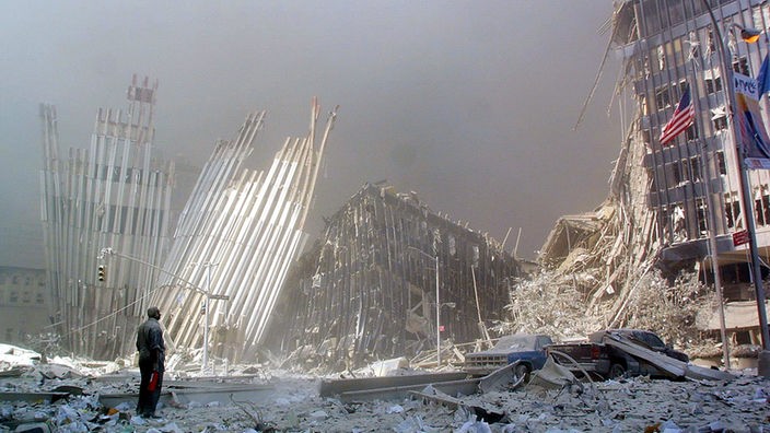 Ein Mann steht nach dem Einsturz der Zwillingstürme auf den Trümmern des World Trade Center in New York