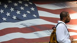 Ein Mann geht an einer gemalten US-Flagge vorbei
