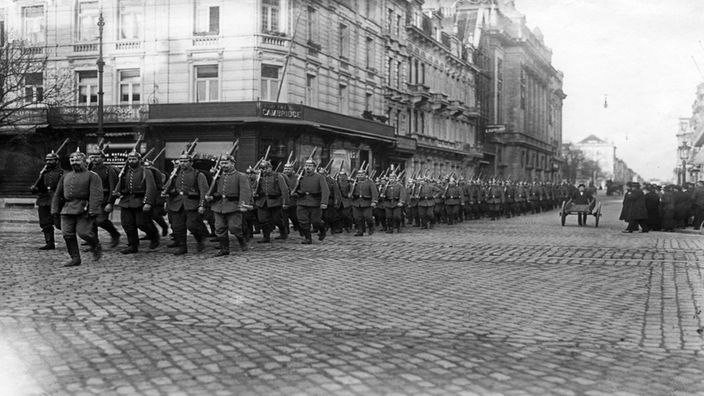 Deutsche Soldaten marschieren durch eine Stadt.