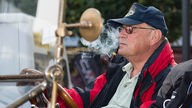 Walter Lippert sitzt Pfeife rauchend in seinem Oldtimer der Marke Overland