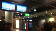 Passagiere blicken auf Monitore am Düsseldorfer Flughafen