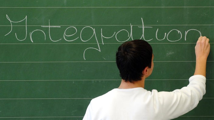 Ein Schüler schreibt das Wort "Integration" auf eine Tafel
