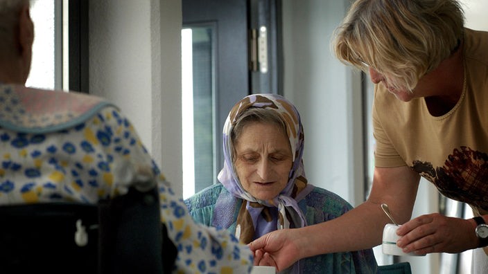 Eine tuerkische Bewohnerin eines Seniorenzentrums bekommt von einer Pflegerin Kaffee