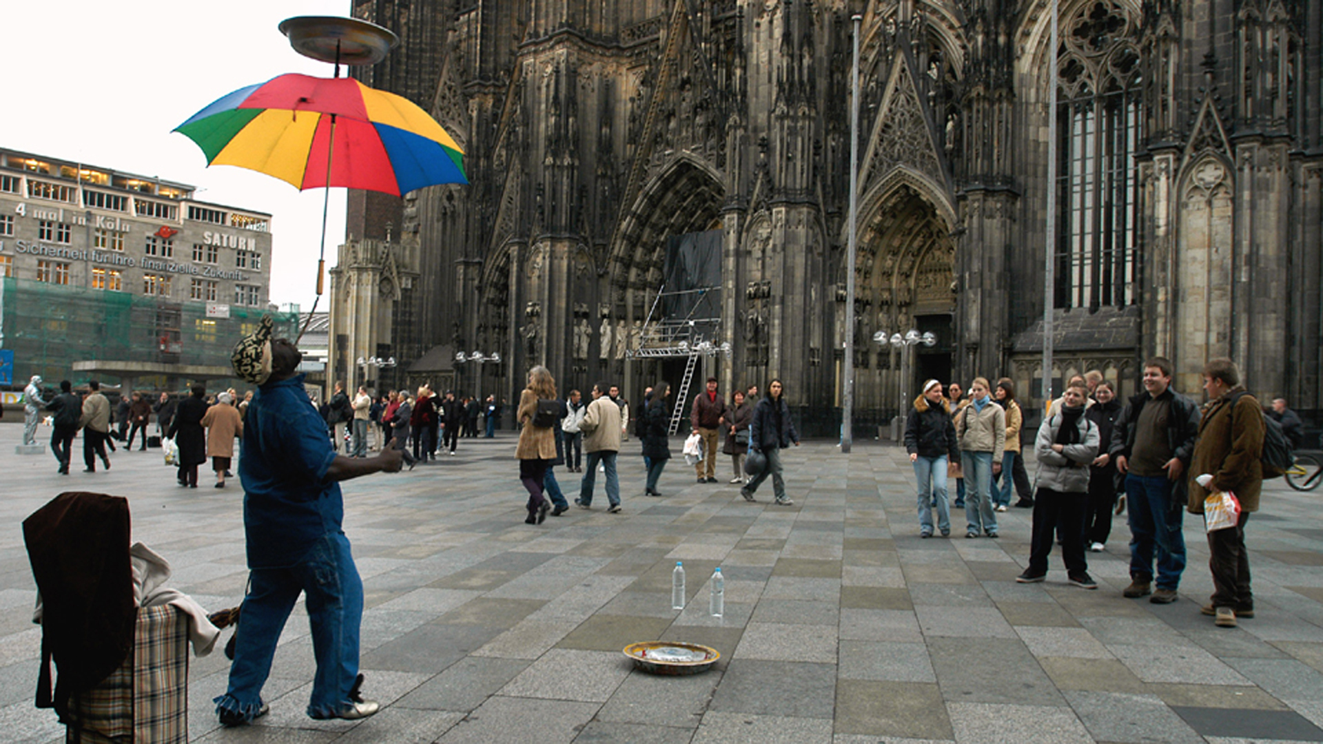 Ein dunkelhäutiger Artist zeigt auf der Platte vor dem Kölner Dom ein Kunststück