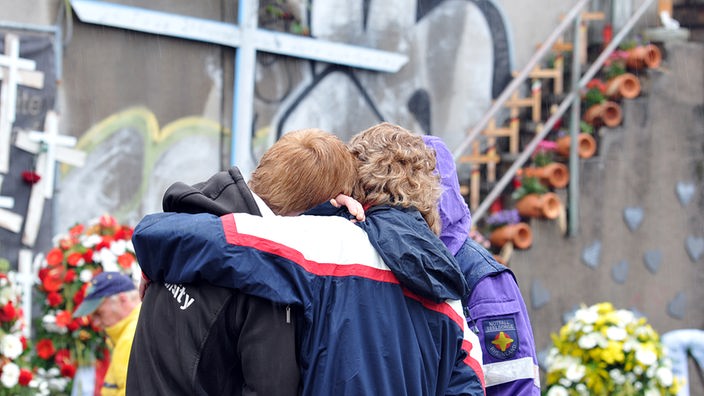 Jugendliche umarmen sich am Unglücksort der Loveparade
