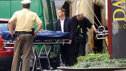 Ein Bestatter schiebt am Mittwoch (15.08.07) am Tatort einer Schiesserei in Duisburg eine Bahre, auf der ein Opfer liegt, zum Leichenwagen. 
