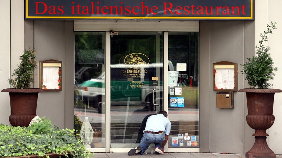 Ein Ermittler kniet am Eingang des Restaurants Da Bruno