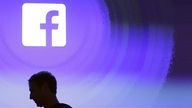 Facebook-Logo, vor dem die Umrisse von Mark Zuckerbergs Kopf zu sehen sind.