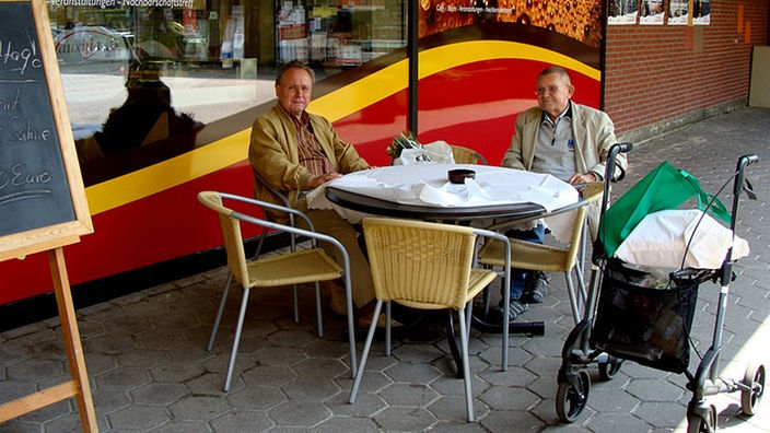 Rentner sitzen vor einem Café