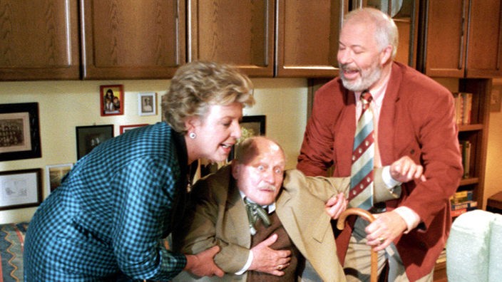 Helga (Marie-Luise Marjan) und Erich (Bill Mockridge, rechts) komplimentieren Onkel Franz (Franz Wittich) schnell aus der Wohnung.