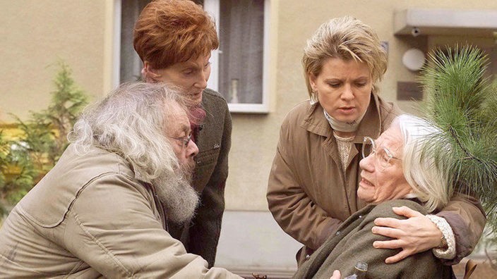 Schreck beim Wandertag: Harry (Harry Rowohlt, links), Rosi (Margret van Munster, 2.v.l.) und Gabi (Andrea Spatzek) kümmern sich um Frau Birkhahn (Hanna Burgwitz), die auf der Straße zusammen geklappt ist.