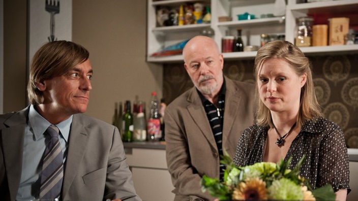 Tanja, ihr Anwalt und Erich sitzen in Tanjas Küche