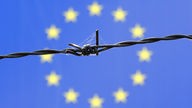 Symbolfoto EU-Grenze mit Stacheldrahtzaun vor EU-Fahne