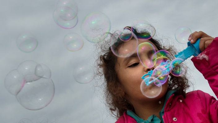 Ein kleines Mädchen macht Seifenblasen