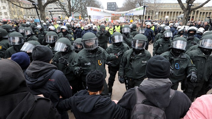 Polizisten mit Schutzhelden bei einer Demonstration umringt von Demonstranten