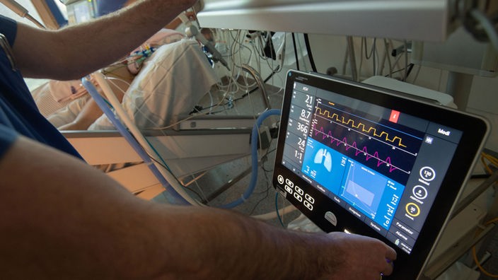 Ein Arzt bedient eine Beatmungsmaschine auf einer Intensivstation.