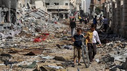 Palästinenser laufen durch eine zerstörte Straße in Gaza (24.11.2023)
