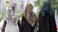 Drei junge Frauen mit Kopftüchern gehen durch die  Innenstadt von München