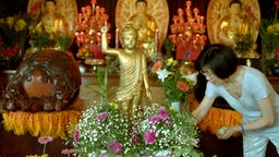 Eine Frau schmückt eine Buddha-Statue