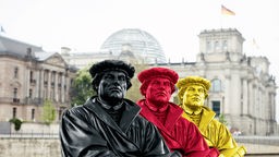 Drei farbige Lutherstatuen vor dem Berliner Reichstag