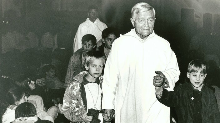 Frère Roger hält zwei Kinder an der Hand bei einem Taizé-Treffen 1993 in München