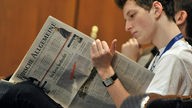 Junger Mann liest jüdische Wochenzeitung