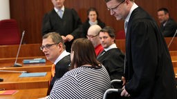 Annas Pflegemutter(M) wird von ihrem Anwalt Christian Breuer (r) im Rollstuhl in den Gerichtssaal gefahren