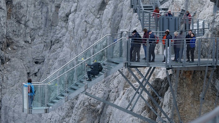 Menschen auf der Treppe ins Nichts in den Alpen