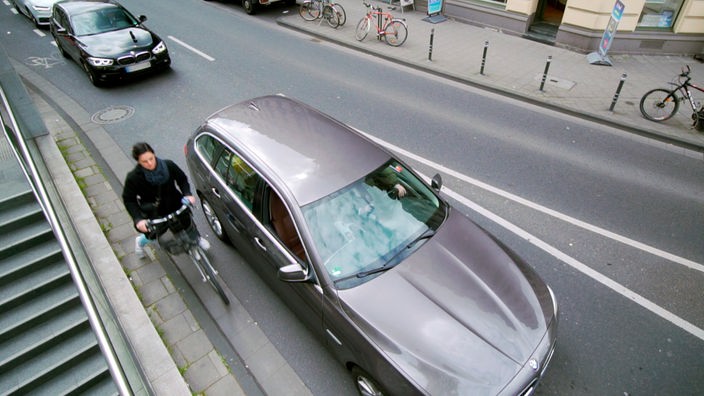 Radfahrerin auf der Straße dicht an einem Auto