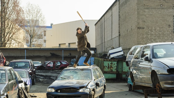Peter Faber (Jörg Hartmann) schlägt mit einem Baseballschläger auf ein Auto ein.