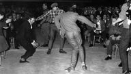 Begeisterte Jugendliche in den fünfziger Jahren, so genannte "Halbstarke", tanzen ausgelassen.