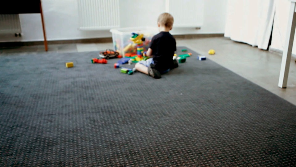 Ein kleines Kind sitzt auf dem Teppich und spielt