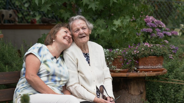 Tochter und Mutter (sehr alt) lachen gemeinsam und sitzen im Park