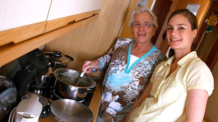 Ein ältere und eine junge Frau stehen in der Küche am Herd