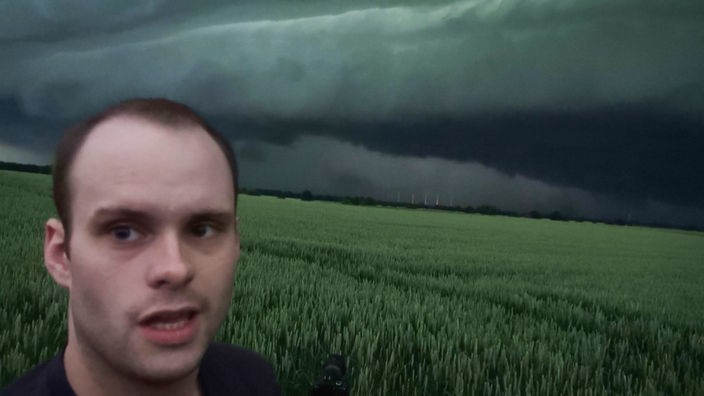 Ein Mann im Vordergrund, im Hintergrund eine dunkle Gewitterfront