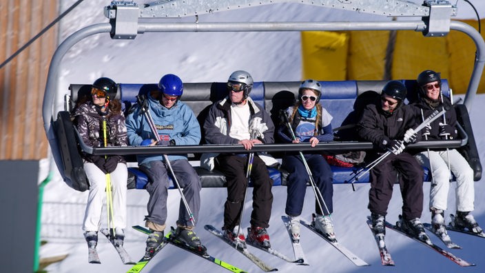 Menschen in Skikleidung sitzen in einem Sessellift