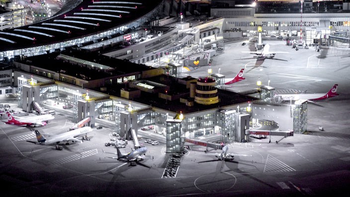 Bei Nacht hell erleuchteter Flughafen Düsseldorf mit parkenden Maschinen rund um die Terminals
