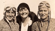 Drei junge Frauen auf einer 20er Jahre Fotografie, davon zwei mit Fliegerhauben