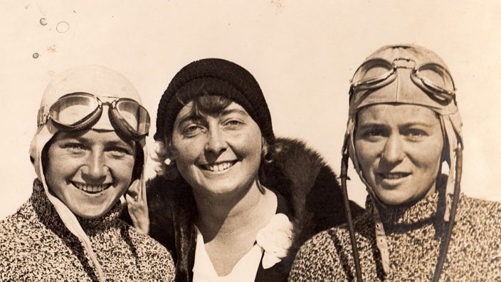 Drei junge Frauen auf einer 20er Jahre Fotografie, davon zwei mit Fliegerhauben