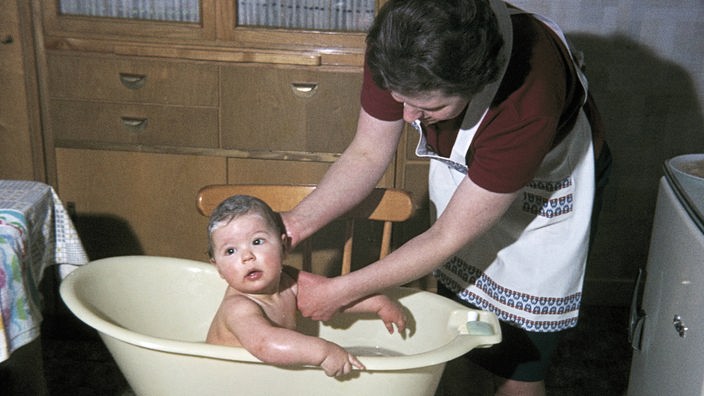 Eine Frau badet ein Baby in einer Badewanne