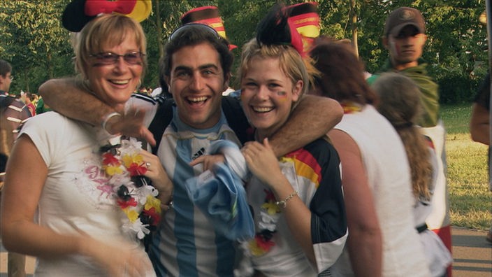 Ein argentinischer Fan feiert mit zwei weiblichen deutschen Fans