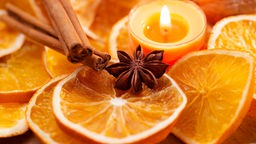 Orangenscheiben, Zimtstangen und Sternanis mit Kerze