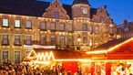 Menschen auf dem Weihnachtsmarkt mit dem Rathaus in Düsseldorf.