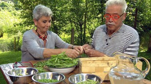 Martina Meuth und Bernd Neuner-Duttenhofer sitzen an einem Gartentisch und pulen Erbsen aus