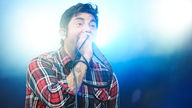 Sänger der Band Deftones brüllt ins Mikrofon vor einem blauen Hintergrund 