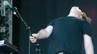 Sänger The Wombats hält das Mikrofon richtung Publikum und schlägt den Kopf nach hinten