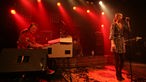 Die Bühne ist in rotes Licht getaucht, Julie Discroll steht auf der Bühne und singt, links daneben spielt Brian Auger am Keyboard